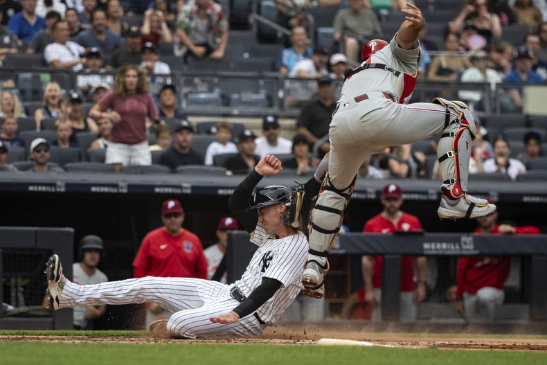Cody Bellinger, izquierda, de los Yankees de Nueva York, es puesto out en el plato por el receptor J.T. Realmuto, derecha, de los Filis de Filadelfia, durante la tercera entrada del juego de béisbol de Grandes Ligas, el domingo 27 de julio de 2025, en Nueva York. (AP Foto/Angelina Katsanis)