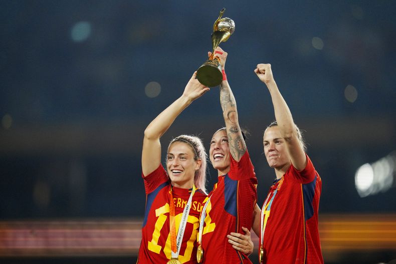 En esta imagen de archivo (de izquierda a derecha), las futbolistas de la selección española Alexia Putellas, Jennifer Hermoso e Irene Paredes posan con el trofeo tras ganar la Copa del Mundo femenina al superar a Inglaterra en la final, en el Estadio Australia, en Sidney, Australia, el 20 de agosto de 2023. España examina el sexismo en el fútbol luego de que el jefe de la RFEF propinó un beso no consentido a una jugadora en la Copa del Mundo. (AP Foto/Abbie Parr, archivo)