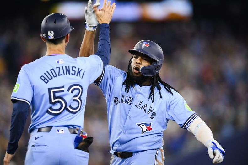 El dominicano Vladimir Guerrero Jr. festeja con Mark Budzinski, su compañero de lso Azulejos de Toronto, tras pegar un sencillo de dos carreras en el duelo del sábado 11 de mayo de 2024 ante los Mellizos de Minnesota (Chris Katsarov/The Canadian Press via AP)