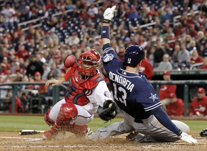 El catcher venezolano Jos&eacute; Lobat&oacute;n, izquierda, de los Nacionales de Washington no logra poner out a Chris Denorfia de los Padres de San Diego, que logra anotar remolcado por un doble de Seth Smith, en un partido en el Nationals Park, el juev