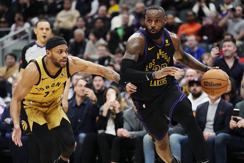 LeBron James, alero de los Lakers de Los Ángeles, elude a Bruce Brown, de los Raptors de Toronto, en el duelo del martes 2 de abril de 2024 (Frank Gunn/The Canadian Press via AP)