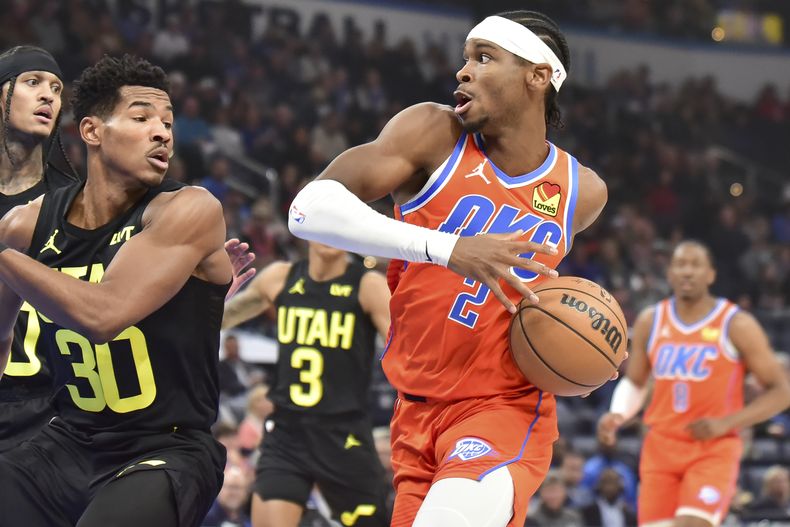 Shai Gilgeous-Alexander (2) del Thunder de Oklahoma City penetra al aro ante Ochai Agbaji (30) del Jazz de Utah, el lunes 11 de diciembre de 2023, en Oklahoma City. (AP Foto/Kyle Phillips)