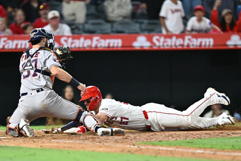 Mike Trout, derecha, de los Angelinos de Los Ángeles, se barre en el plato pero es puesto fuera en la décima entrada del juego de béisbol de Grandes Ligas, el lunes 8 de junio de 2026, en Anaheim, California. (AP Foto/William Liang)