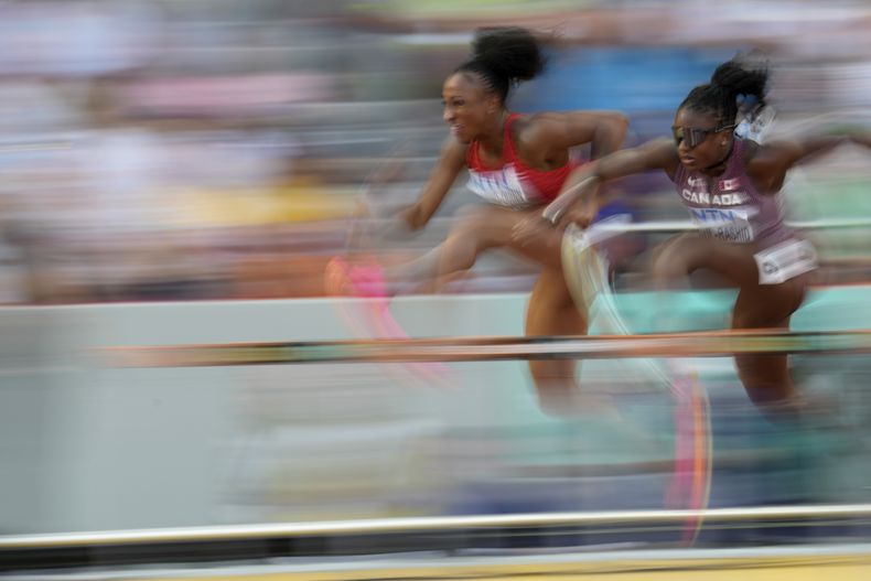 La boricua Jasmine Camacho-Quinn y la canadiense Mariam Abdul-Rashid compiten en las preliminares de los 100 metros con vallas del Mundial de atletismo, el martes 22 de agosto de 2023, en Budapest (AP Foto/Ashley Landis)