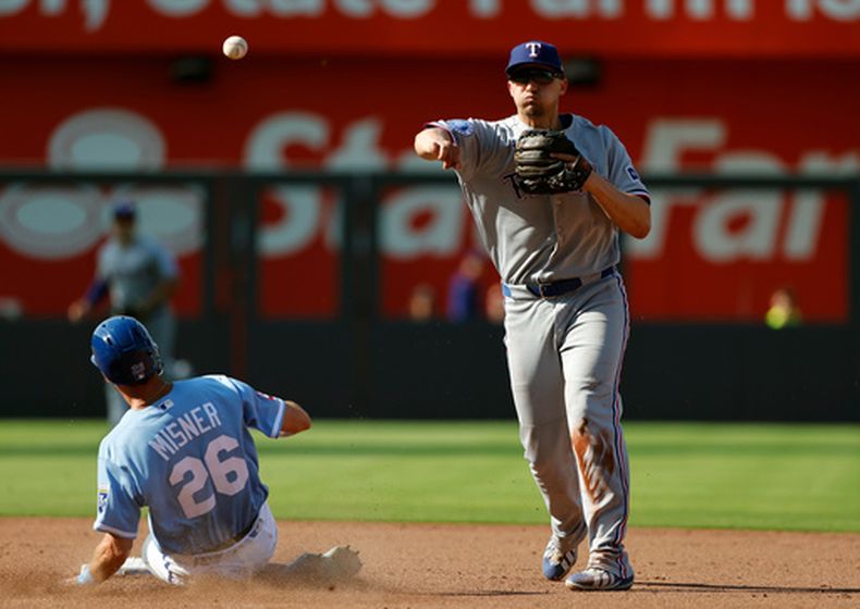 Kameron Misner (26), de los Reales de Kansas City, es puesto fuera en segunda base mientras el campo corto de los Rangers de Texas, Corey Seager, derecha, lanza a primera para completar una jugada de doble play en la séptima entrada del juego de béisbol de Grandes Ligas del jueves 11 de junio de 2026, en Kansas City, Missouri. (AP Foto/Colin E. Braley)