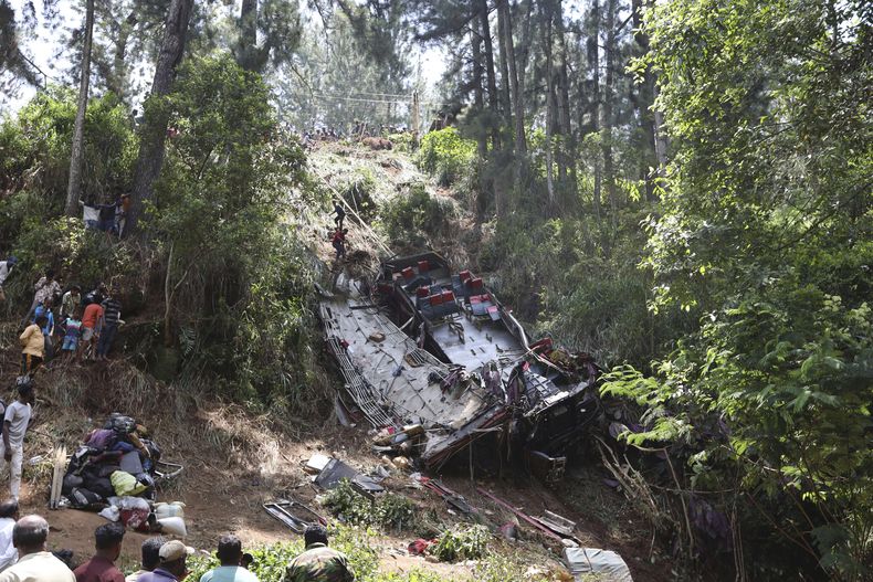 Testigos miran mientras los rescatistas buscan entre los restos de un autobús accidentado cerca de la localidad de Kotmale, Sri Lanka, le domingo 11 de mayo de 2025. (AP Foto)