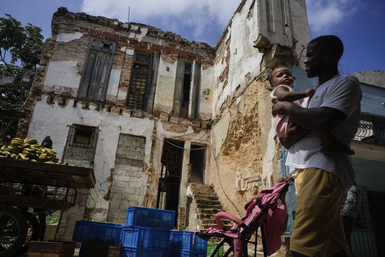 Residentes caminan al frente de la deteriorada mansión de la calle Villegas en La Habana, Cuba, el jueves 5 de octubre de 2023. El edificio de dos pisos, que alberga a seis familias, fue alguna vez una lujosa casa que colapsó parcialmente en los últimos años con evidentes daños. (AP Foto/Ramón Espinosa)