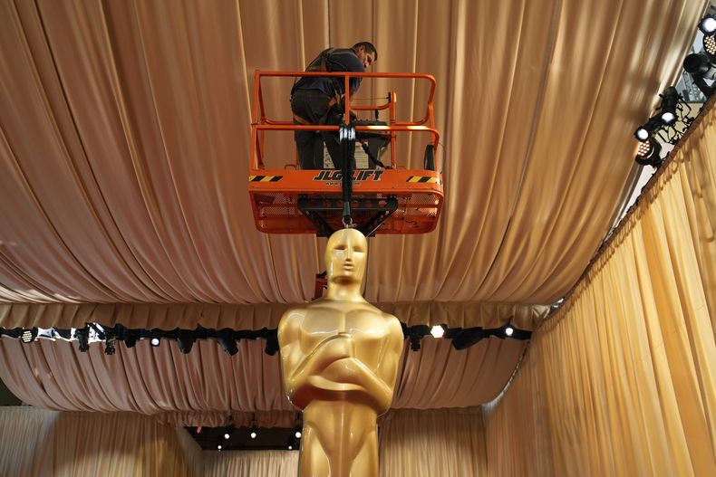 Un trabajador ayuda a colocar una estatua de los Oscar en la alfombra roja previo a la 96a entrega de los Premios de la Academia el sábado 9 de marzo de 2024, en Los Angeles. (Foto AP/John Locher)