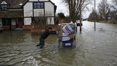 americateve | Un residente local empuja un carrito con algunas pertenencias en &eacute;l en la parte inundada por tormentas del poblado Staines-upon-Thames, Inglaterra, mientras un veh&iacute;culo policial patrulla el &aacute;rea, el mi&eacute;rcoles 12 de febrero de 2