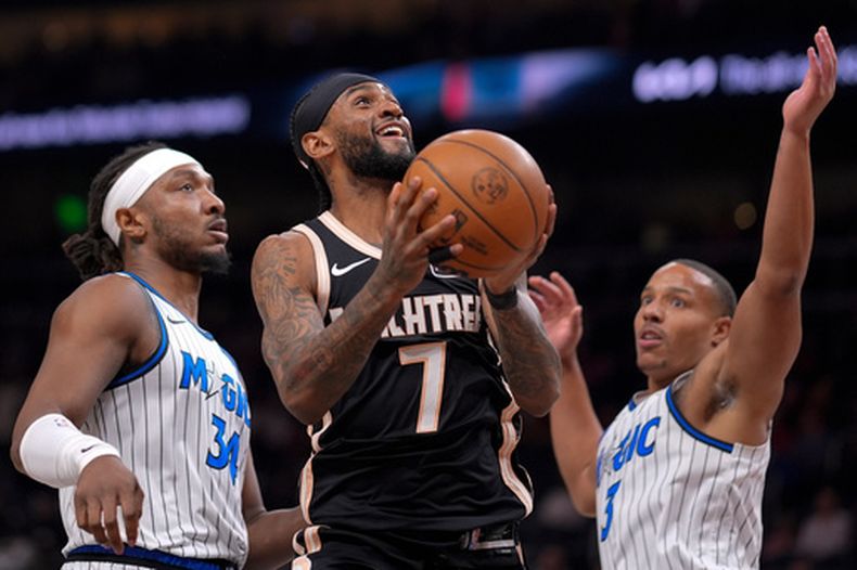 Nickeil Alexander-Walker (7), de los Hawks de Atlanta, se alista para encestar frente a Desmond Bane (3), del Magic de Orlando, durante la primera mitad del juego de baloncesto de la NBA, el lunes 16 de marzo de 2026, en Atlanta. (AP Foto/Mike Stewart)