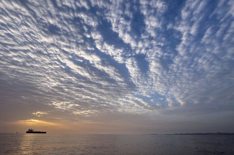 El sol sale detrás de un buque cisterna anclado en el estrecho de Ormuz, frente a la costa de la isla Qeshm, Irán, el sábado 18 de abril de 2026. (AP Foto/Asghar Besharati)
