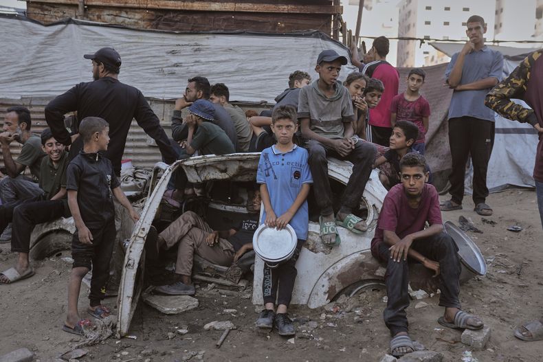 Palestinos esperan alimentos donados en una cocina comunitaria en Ciudad de Gaza, en el norte de la Franja de Gaza, el lunes 14 de julio de 2025. (AP Foto/Jehad Alshrafi)