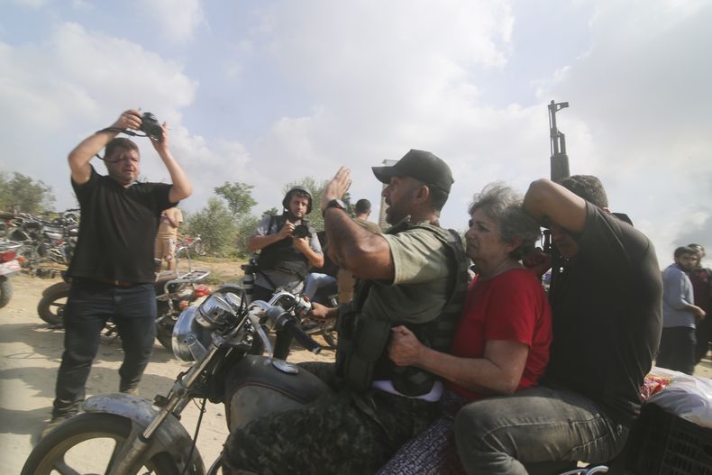Palestinos llevan a una civil israelí capturada (centro) desde el kibutz de Kfar Azza a la Franja de Gaza, el 7 de octubre de 2023. Hamás, el grupo insurgente que gobierna la Franja de Gaza, llegó a cabo un ataque sin precedentes y por varios frente sobre Israel al amanecer del 7 de octubre, disparando miles de proyectiles mientras docenas de combatientes cruzaban la fortificada frontera para infiltrarse en varias localidades por tierra, mar y aire, tomando al país por sorpresa durante un importante feriado. (AP Foto)