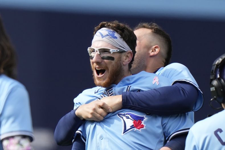 Danny Jansen, de los Azulejos de Toronto, es abrazado por su compañero de equipo Matt Chapman después de batear sencillo productor de dos carreras para ganarle a los Bravos de Atlanta, durante la novena entrada del juego de béisbol, en Toronto, el domingo 14 de mayo de 2023. (Frank Gunn/The Canadian Press vía AP)