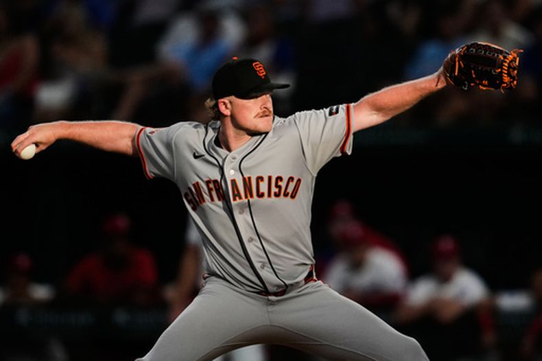 El lanzador de los Gigantes de San Francisco, Logan Webb, lanza a los Rangers de Texas en la primera entrada de un partido de béisbol en Arlington, Texas, el lunes 3 de agosto de 2026. (Foto AP/Tony Gutierrez)