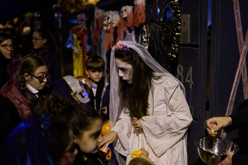 Personas disfrazadas con trajes terroríficos participan en una celebración de Halloween en la que se reparten dulces a los niños en Paracuellos del Jarama, España, el viernes 31 de octubre de 2025. (Foto AP/Manu Fernández)