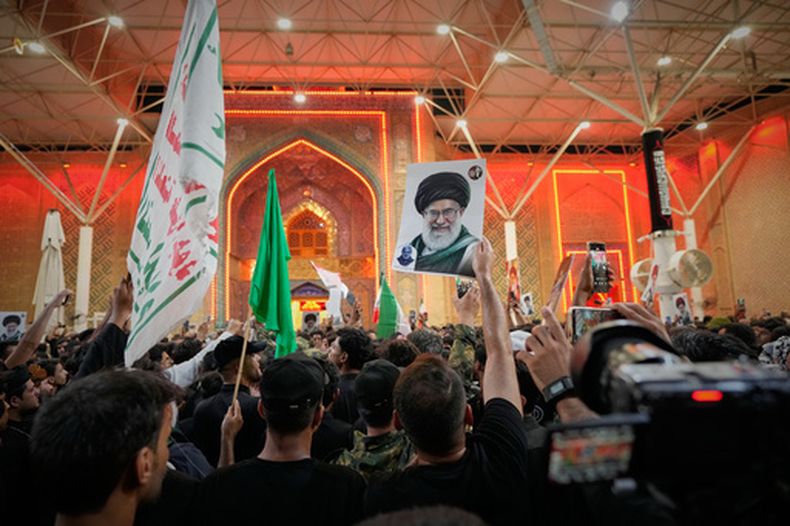 Dolientes ondean banderas religiosas chiíes y un retrato del difunto líder supremo de Irán, el ayatolá Ali Jamenei, en el exterior del mausoleo del imán Ali en la víspera de las ceremonias funerarias, en Najaf, Irak, el 7 de julio de 2026. (AP Foto/Hadi Mizban)