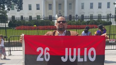 kcho poso con la bandera 26 de julio frente a la casa blanca