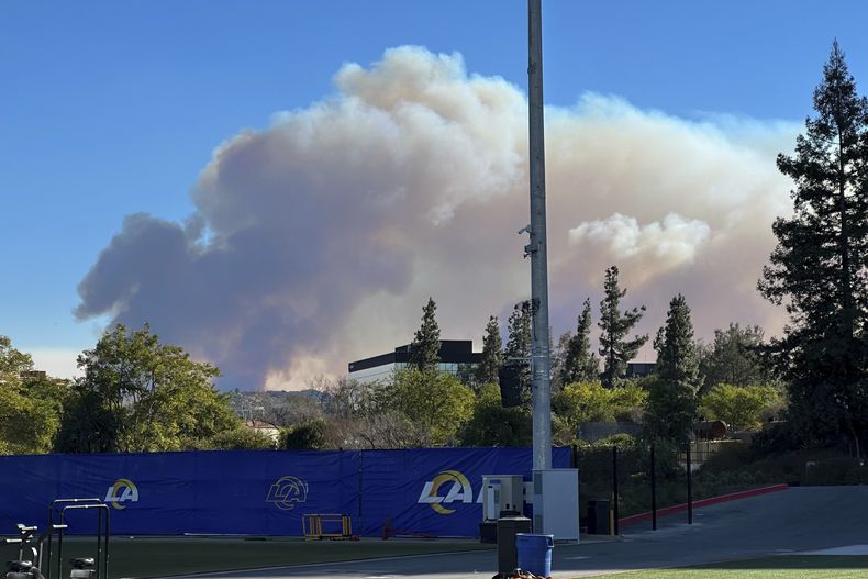 El humo de un incendio forestal se eleva detrás de las instalaciones de entrenamiento de los RAms de Los Ángeles en Woodland Hills, el jueves 9 de enero de 2025 (AP Foto/Greg Beacham)