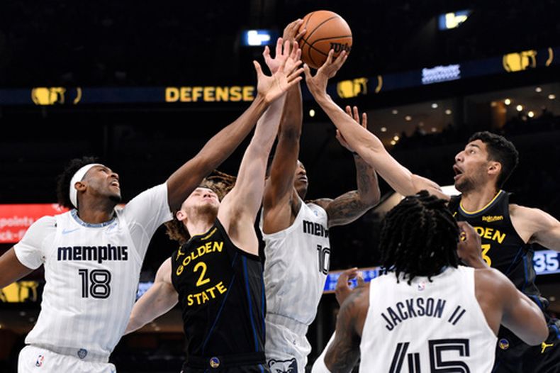 Olivier-Maxence Prosper (18), Brandin Podziemski (2), Javon Small (10) y Malevy Leons, extrema derecha, jugadores de los Grizzlies de Memphis y Warriors de Golden State, disputan un balón en la primera mitad del juego de baloncesto de la NBA del miércoles 25 de febrero de 2026, en Memphis, Tennessee. (AP Foto/Brandon Dill)