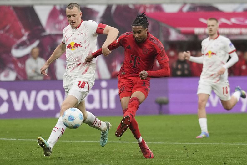 Michael Olise del Bayern Munich intenta disparar mientras lo defiende Lukas Klostermann del Leipzig en el encuentro de la Bundesliga del sábado 3 de mayo del 2025. (AP Foto/Matthias Schrader)