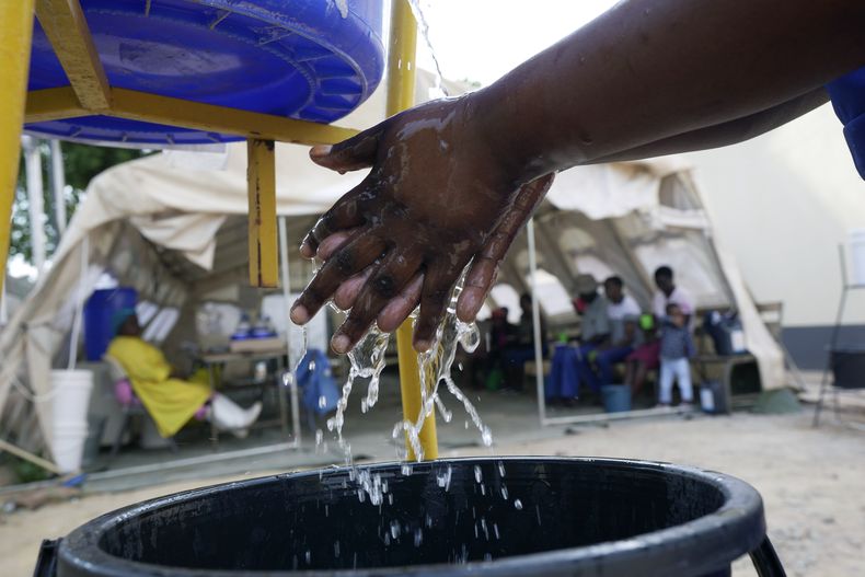 Una mujer se lava las manos antes de entrar a una carpa con pacientes de cólera en Harare, Zimbabue, el domingo 19 de noviembre de 2023. (AP Foto/Tsvangirayi Mukwazhi)