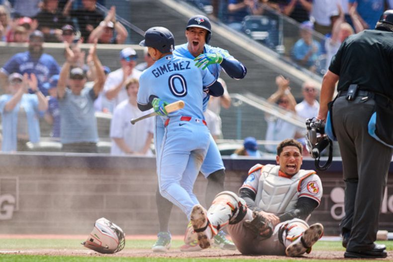 Andrés Giménez (0), de los Azulejos de Toronto, celebra con George Springer (segundo desde la izquierda) tras anotar gracias a un sencillo conectado por Nathan Lukes (no aparece en la foto) contra los Orioles de Baltimore, durante la acción de la sexta entrada de un partido de béisbol en Toronto, el domingo 7 de junio de 2026. (Sammy Kogan/The Canadian Press vía AP)