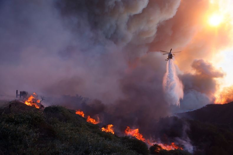 ARCHIVO - Un helicóptero arroja agua sobre el incendio Palisades, que avanza en el vecindario Pacific Palisades de Los Ángeles, el 7 de enero de 2025. (Foto AP/Etienne Laurent, archivo)