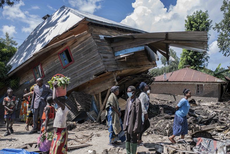 La gente camina junto a una casa destruida por las inundaciones en la aldea de Nyamukubi, provincia de Kivu del Sur, en la República Democrática del Congo, el sábado 6 de mayo de 2023. (Foto AP/Moisés Sawasawa)