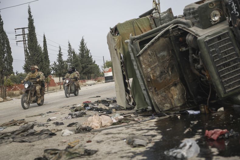 Combatientes de oposición sirios pasan junto a un vehículo dañado del gobierno al sur de Hama, Siria, el sábado 7 de diciembre de 2024. (AP Foto/Ghaith Alsayed)