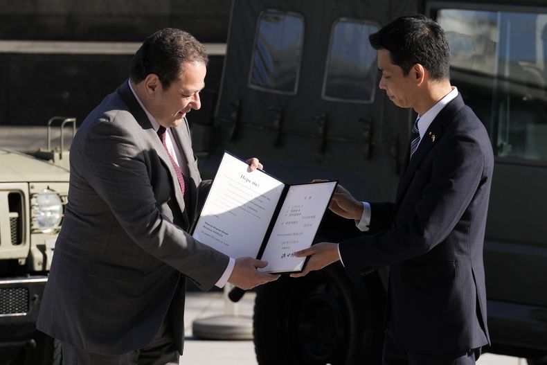 El embajador de Ucrania a Japón, Sergiy Korsunsky, centro, recibe un documento del viceministro de Defensa, Toshiro Ino, durante la ceremonia de entrega de equipo de defensa para Ucrania en el Ministerio de Defensa, Tokio, miércoles 24 de mayo de 2023. (AP Foto/Eugene Hoshiko)