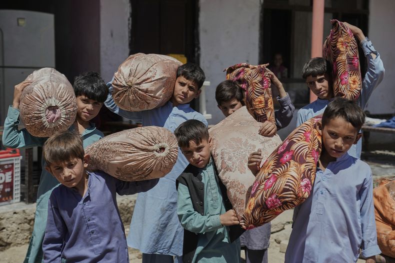 Niños afganos de familias repatriadas de Pakistán cargan cojines mientras se desplazan a su nuevo lugar de residencia, en Kabul, Afganistán, el martes 3 de junio de 2025. (AP Foto/Ebrahim Noroozi)