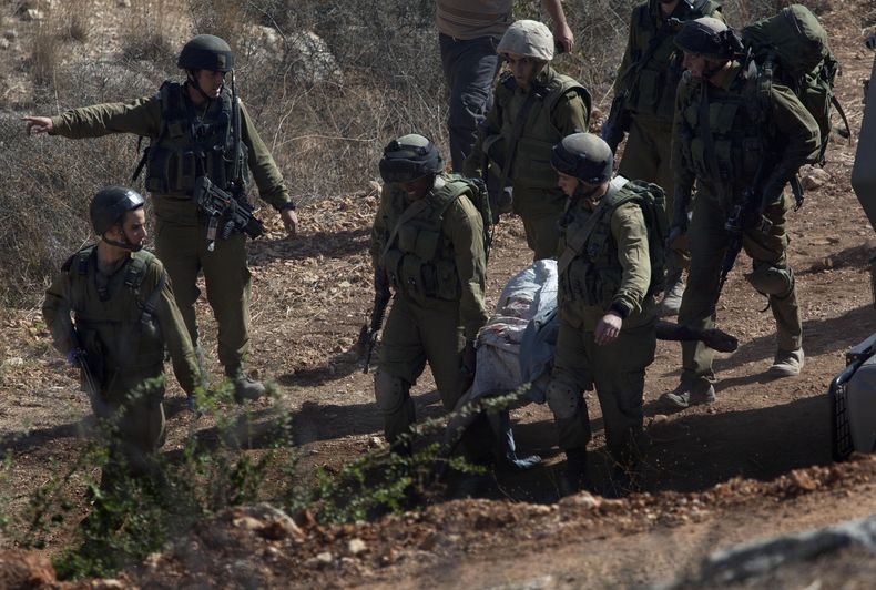 Soldados israel&iacute;es cargan el cad&aacute;ver de Mohamed Aatzi, extremista palestino de la Yihad Isl&aacute;mica, hacia un veh&iacute;culo del ej&eacute;rcito cerca del poblado de Bilin, a poca distancia de la ciudad cisjordana de Ramal&aacute;, el m