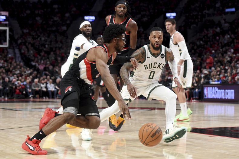 Scoot Henderson, base de los Trail Blazers de Portland, avanza a la cesta junto a Damian Lillard, de los Bucks de Milwaukee, el miércoles 31 de enero de 2024 (AP Foto/Steve Dykes)