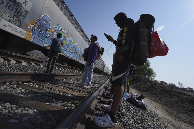 ARCHIVO - Migrantes miran un tren pasar mientras esperan en las vías con la esperanza de poder abordar uno que vaya hacia el norte, uno que se detenga el tiempo suficiente para que se puedan subir, en Huehuetoca, México, el 12 de mayo de 2023, el día después de la finalización del Título 42 que imponía restricciones al asilo relacionadas con la pandemia. Sin quererlo, las personas migrantes en América Latina financian la desinformación durante sus trayectos hacia Estados Unidos, pues son víctimas de fraudes y engaños que les pueden costar miles de dólares y con los que se sostienen nuevos modelos de negocio, que van desde falsos reclutadores de trabajadores hasta quienes se hacen llamar coaches de migración. (AP Foto/Marco Ugarte, Archivo)