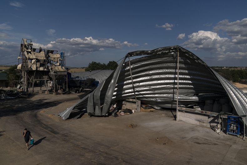 Un empleado camina junto a almacenes dañados en una instalación de granos en Pavlivka, Ucrania, el sábado 22 de julio de 2023, luego de ataques de misiles rusos. (AP Foto/Jae C. Hong)
