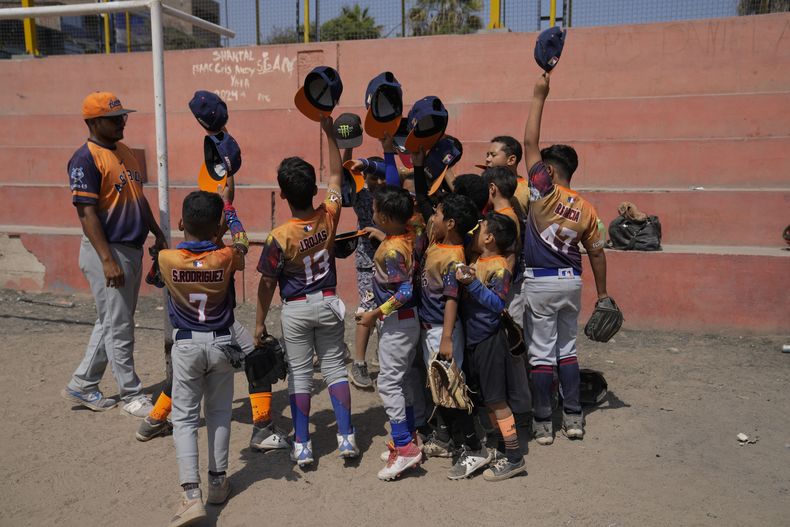 Los Astros celebran tras ganar a los Cachorros, dos equipos venezolanos, en una cancha pública en la zona de San Juan de Lurigancho, a las afueras de Lima, Perú, el sábado 11 de mayo de 2024. Inmigrantes, en su mayoría venezolanos, han abierto cinco academias de béisbol en la capital de Perú. (AP Foto/Martin Mejia)