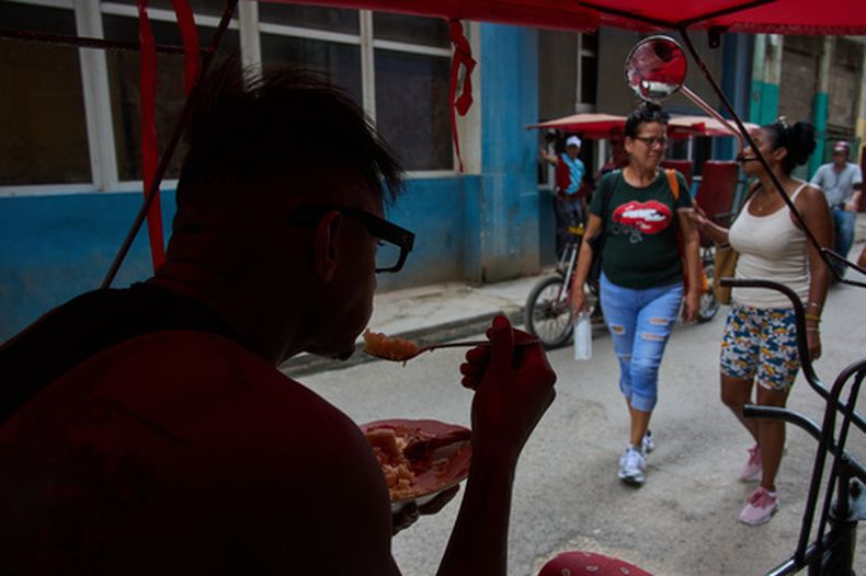Un conductor de bicitaxi come desde su bicicleta durante un apagón en La Habana, Cuba, el lunes 6 de julio de 2026. (AP Foto/Ramón Espinosa)