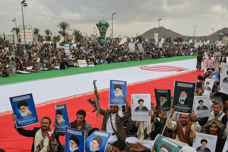 Hutíes sostienen carteles del líder supremo de Irán, el ayatolá Ali Jamenei, que murió en un ataque de Israel y EEUU, junto a una enorme bandera iraní mientras protestan contra la guerra contra Irán, en Saná, Yemen, viernes 6 de marzo de 2026. (Foto AP/Osamah Abdulrahman)