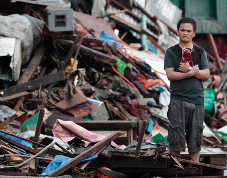 Tras el paso del tifón Haiyan, comienza a llegar ayuda para los damnificados en Filipinas. Un superviviente del tifón Haiyan permanece de pie en silencio entre las casas dañadas en la ciudad de Tacloban, Filipinas, el lunes 11 de noviembre de 2013. (Foto