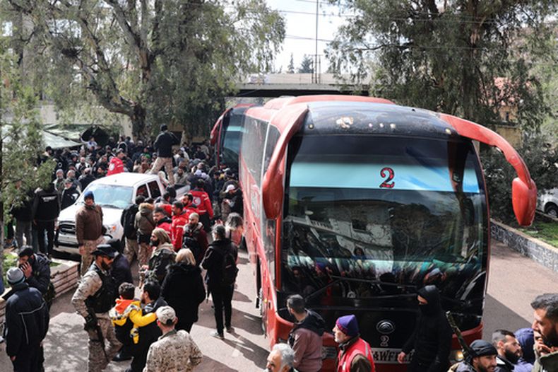 Varias personas esperan junto a un autobús con prisioneros drusos, tras su liberación en un canje entre las fuerzas del gobierno sirio y milicias drusas, en la provincia de Sweida, Siria, el 26 de febrero de 2026. (AP Foto/Fahd Kiwan)