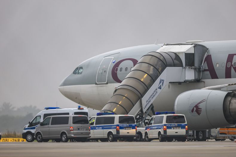 Varias personas embarcan en un avión de Qatar Airways, con vehículos de la policía federal estacionados delante, en la pista del aeropuerto Leipzig/Halle, el 18 de julio de 2025, en Sajonia, Schkeuditz. (Jan Woitas/dpa/dpa vía AP)