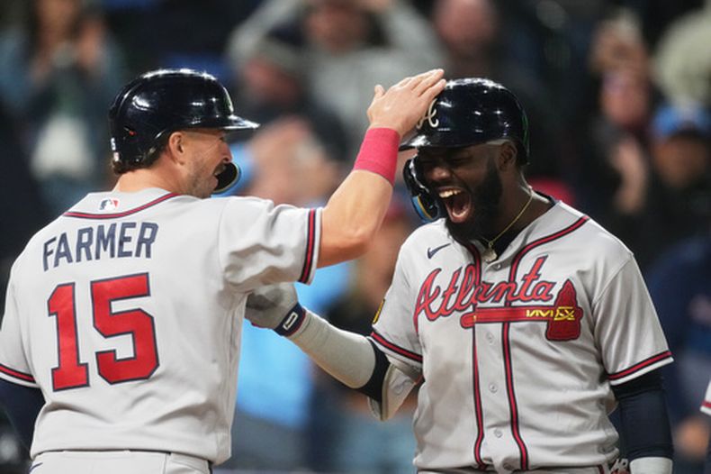 Kyle Farmer, izquierda, de los Bravos de Atlanta, felicita al bateador emergente Michael Harris II, derecha, después del cuadrangular de dos carreras de Harris ante el relevista Juan Mejía, de los Rockies de Colorado, en la novena entrada del juego de béisbol de Grandes Ligas, el viernes 1 de mayo de 2026, en Denver. (AP Foto/David Zalubowski)