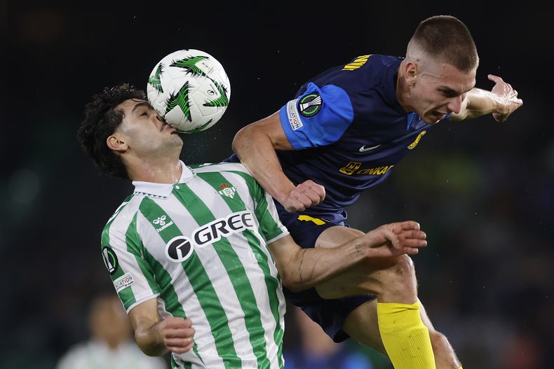 Johnny Cardoso del Betis, derecha, se enfrenta por el balón ante Mark Zabukovnik del Celje durante la Conference League en el estadio Benito Villamarin en Sevilla, España el jueves 7 de noviembre de 2024. (AP Photo/Angel Fernandez)