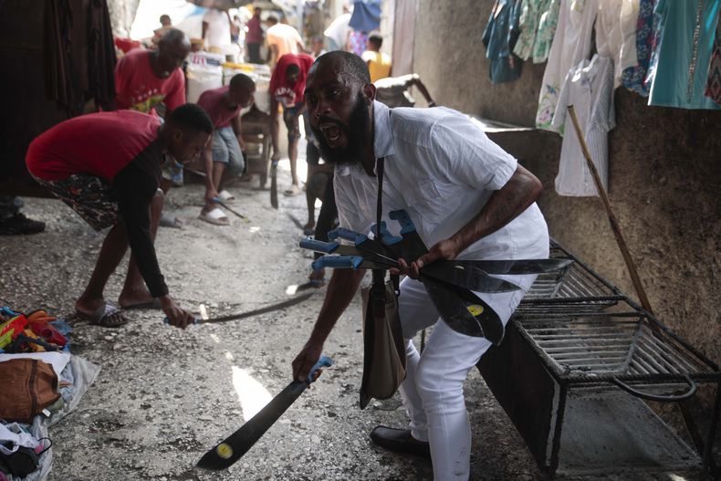 Nertil Marcelin, líder de un grupo comunitario, y miembros de la comunidad golpean machetes contra el suelo el domingo 28 de mayo de 2023, en respaldo al movimiento Bwa Kale, una iniciativa para combatir a pandillas que intentan controlar su vecindario en el distrito Delmas de Puerto Príncipe, Haití. (AP Foto/Odelyn Joseph)