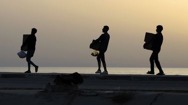 Palestinos cargan cajas con ayuda humanitaria luego de que camiones cargados de ésta llegaron a la Franja de Gaza desde un nuevo muelle flotante erigido por Estados Unidos, en un camino junto a la playa en el campamento de refugiados de Nusseirat, en el centro de la Franja de Gaza, el sábado 18 de mayo de 2024. (AP Foto/Saher Alghorra)