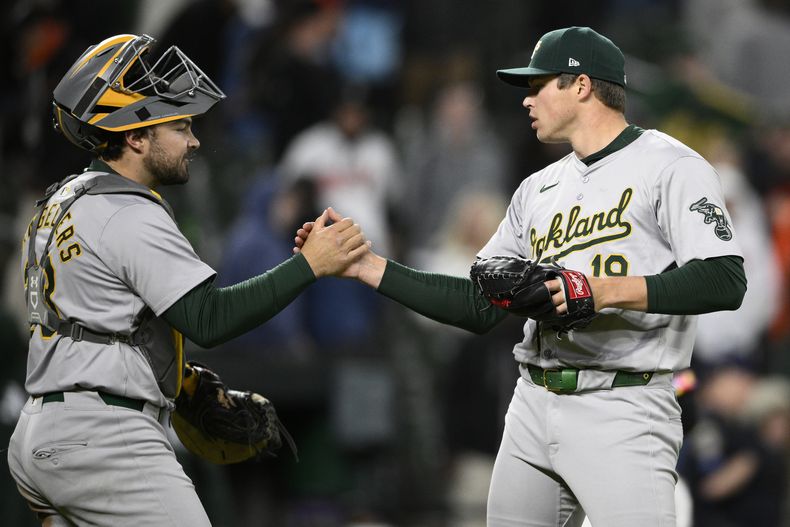El revelista de los Atléticos de Oakland Mason Miller (derecha) celebra junto al receptor Shea Langeliers (izquierda) luego del partido de béisbol ante los Orioles de Baltimore, el viernes 26 de abril de 2024, en Baltimore. (AP Foto/Nick Wass)