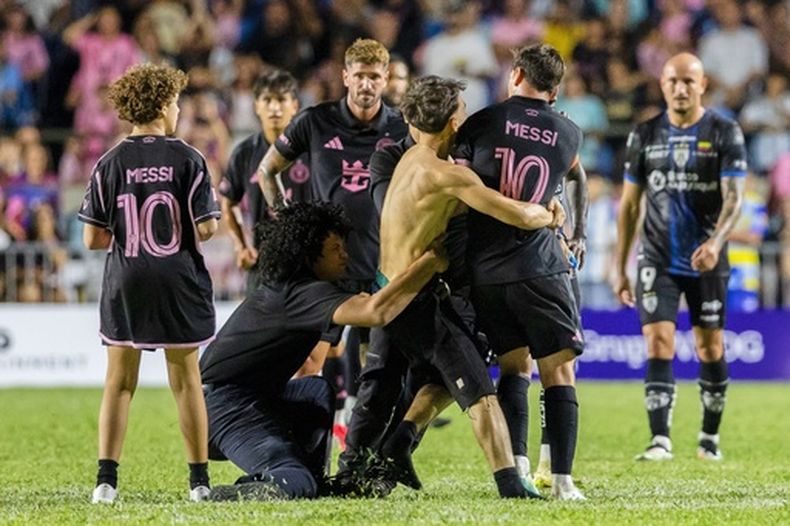 Un aficionado que irrumpió en la cancha sujeta a Lionel Messi al final del partido amistoso entre Inter Miami e Independiente del Valle de Ecuador, el jueves 26 de febrero de 2026, en Bayamón, Puerto Rico. (AP Foto/Alejandro Granadillo)