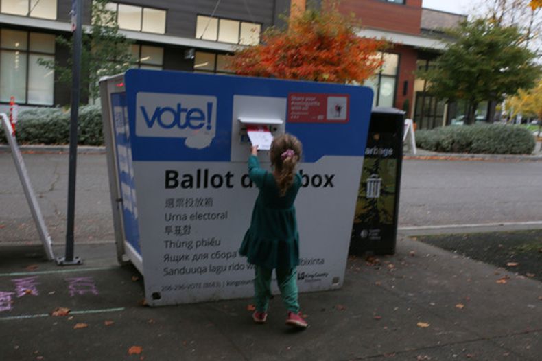 ARCHIVO - Olive, de 4 años, deposita una boleta electoral en un buzón en Seattle, Washington, bajo la supervisión de su madre, el 4 de noviembre de 2025. (AP Foto/Cedar Attanasio/Archivo)