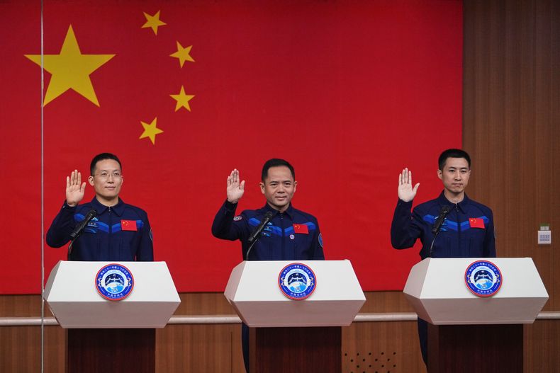 Los astronautas de la próxima misión Shenzhou 21 --de izquierda a derecha, Zhang Hongzhang, Zhang Lu y Wu Fei-- saludan a su llegada a una reunión con la prensa en el Centro de Lanzamiento de Satélites de Jiuquan, el jueves 30 de octubre de 2025, en Jiuquan, noroeste de China. (AP Foto/Andy Wong)